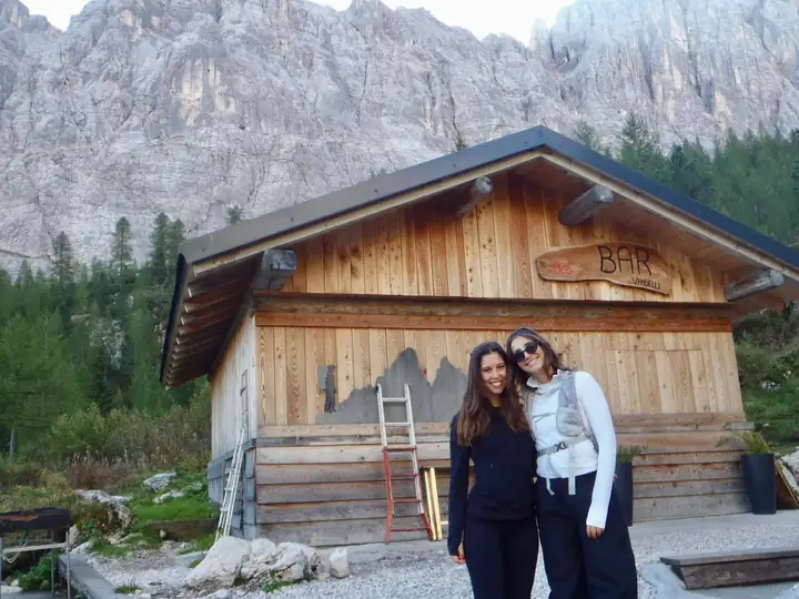 Two friends in front of a wooden mountain hut