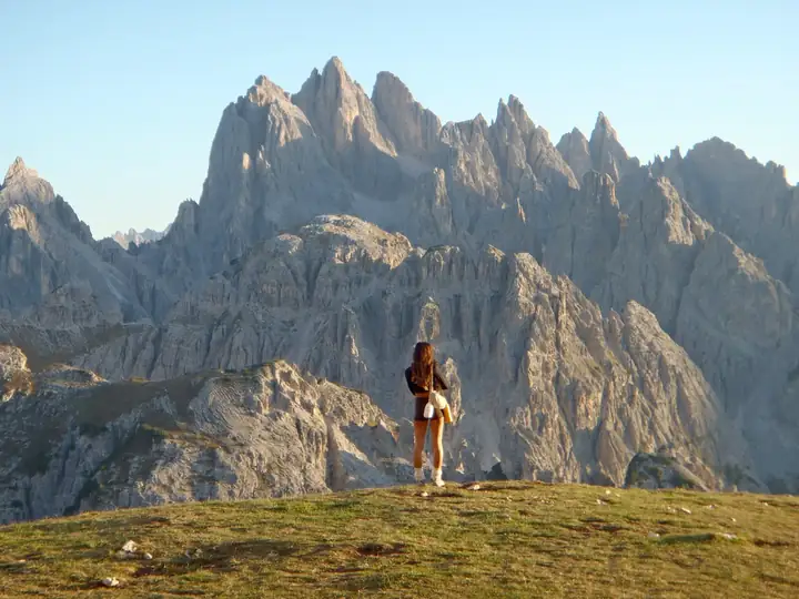 A woman standing before the jagged Cadini peaks