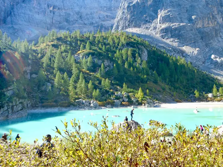 Turquoise lake shore with hikers resting