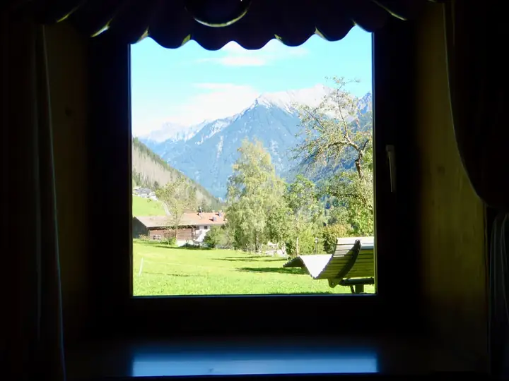 Mountain view framed by a dark chalet window